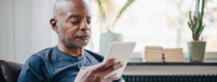Older black man staring intently at a paper to show how the Highmark Medicare cost estimator tool can help you calculate annual costs. 
