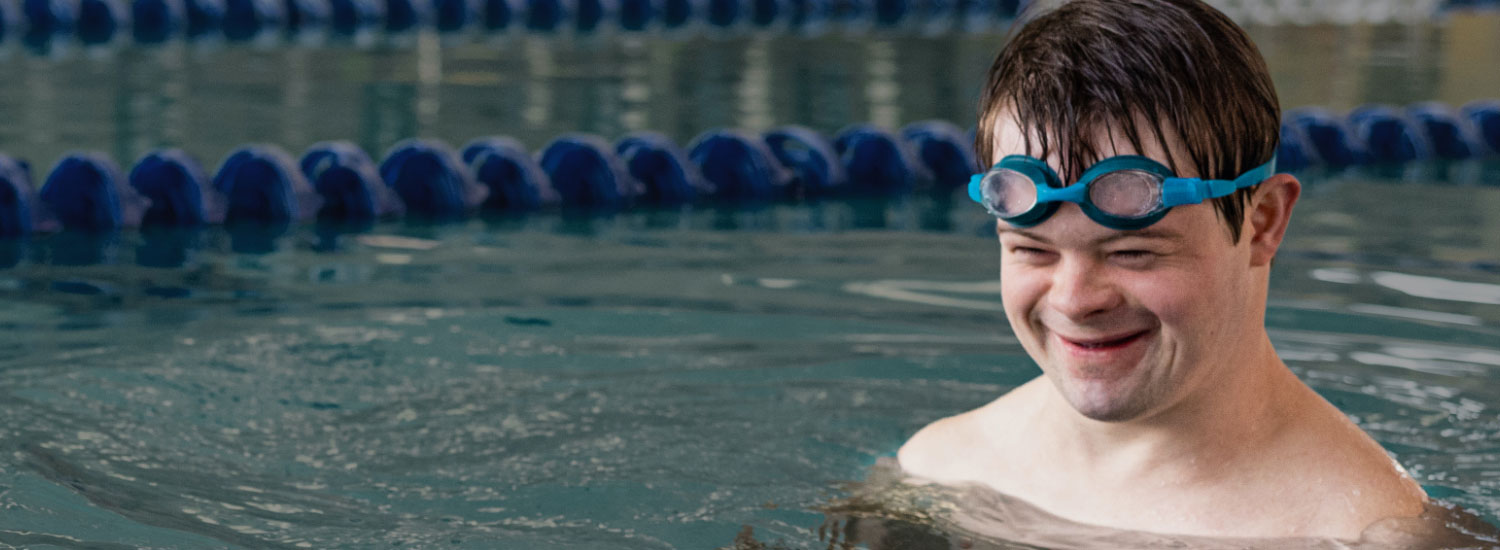 Young man in a pool with goggles pushed up on his head to show Blue Cross Blue Shield Western NY member services