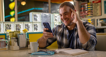 a young adult on his mobile phone at a restaurant 