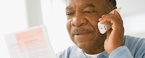 a man looking at a medicare brochure while talking on the phone with a medicare specialist