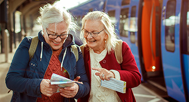 two senior women checking their boarding passes before entering the train