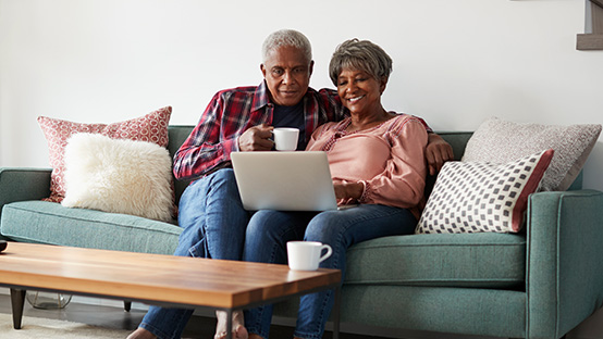 a couple sitting on a couch looking at a laptop computer