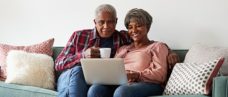 two seniors drinking coffee on their couch and looking into getting the fact on Medicare 101