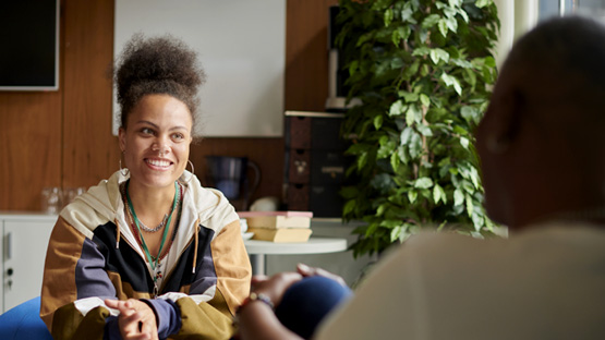 young woman smiling sitting across from another woman talking