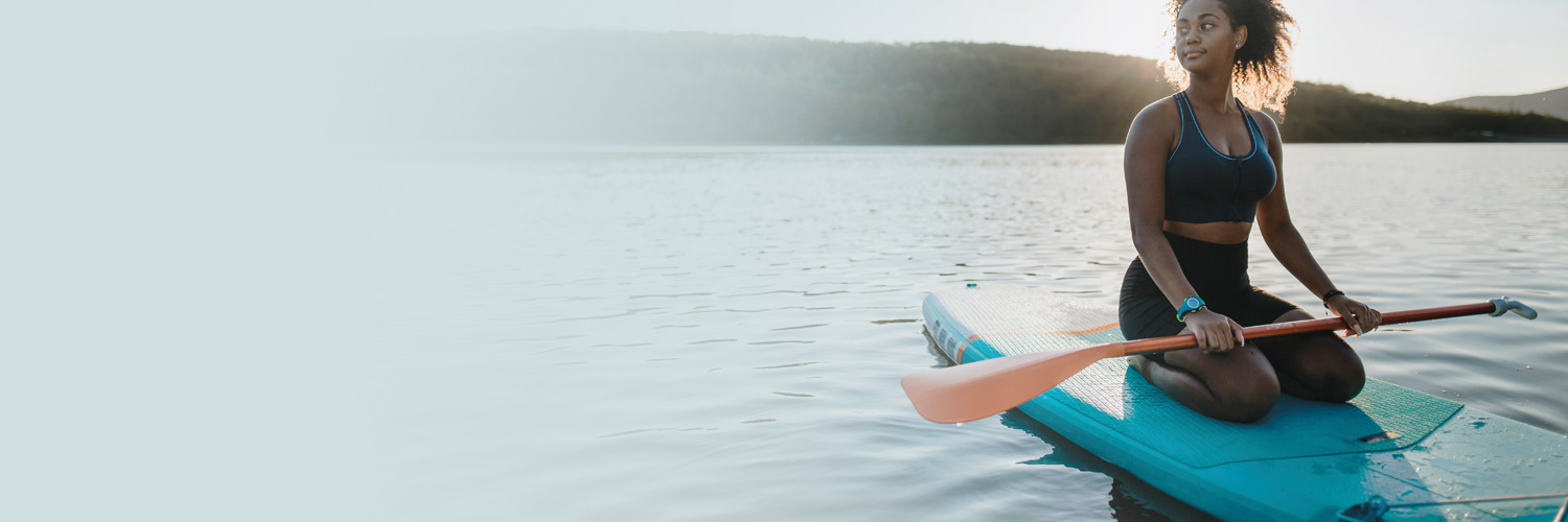 Young woman on a paddleboard in the middle of a lake to illustrate mental heath services